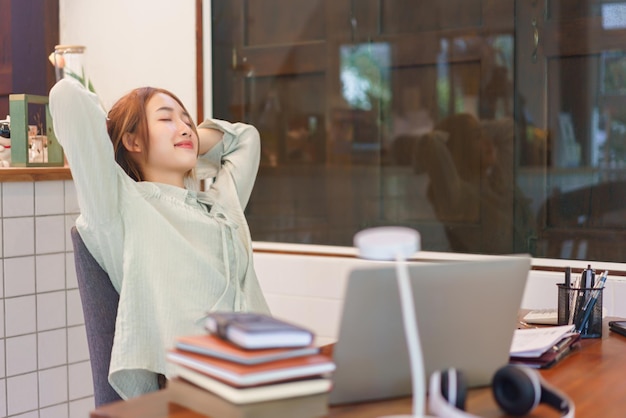 Coworking space office concept Woman entrepreneur puts hands behind head and close eyes to resting