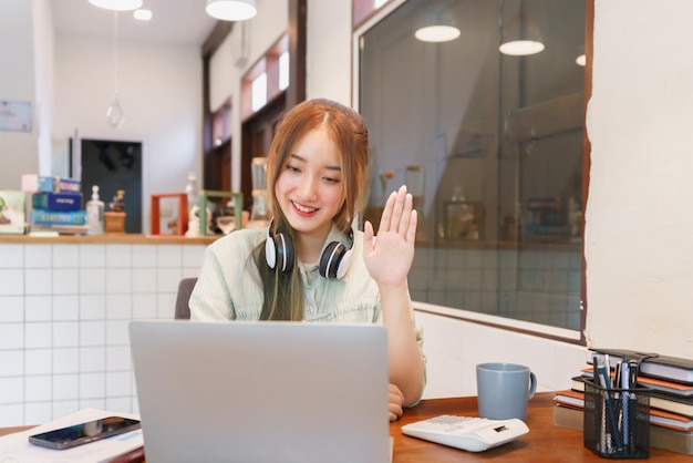 Coworking space office concept Woman entrepreneur talking and greeting colleague on video call