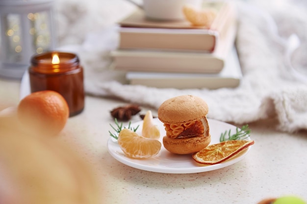 Cozy aesthetics home with macaroon tangerines among books\
candle and cocoa sweet holidays christmas dessert