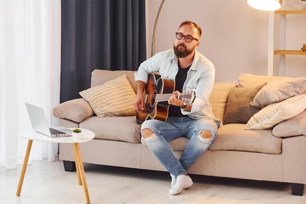 Photo cozy atmosphere man in casual clothes and with acoustic guitar is indoors