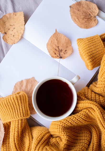 Il clima accogliente del maglione della composizione autunnale tellow lascia il tè caldo e i maglioni