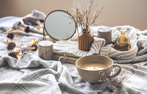 Cozy autumn composition with a cup of coffee and candles in bed