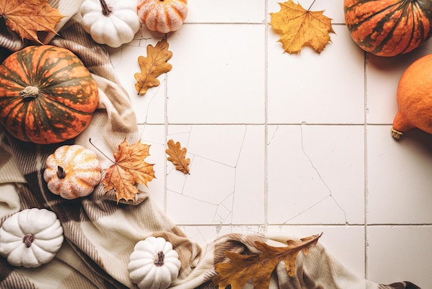 Cozy autumn flat lay with pumpkins plaid and autumn leaves on\
tile background autumn home decor cozy