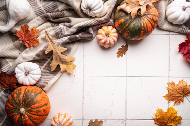 Cozy autumn flat lay with pumpkins plaid and autumn leaves on tile background autumn home decor cozy