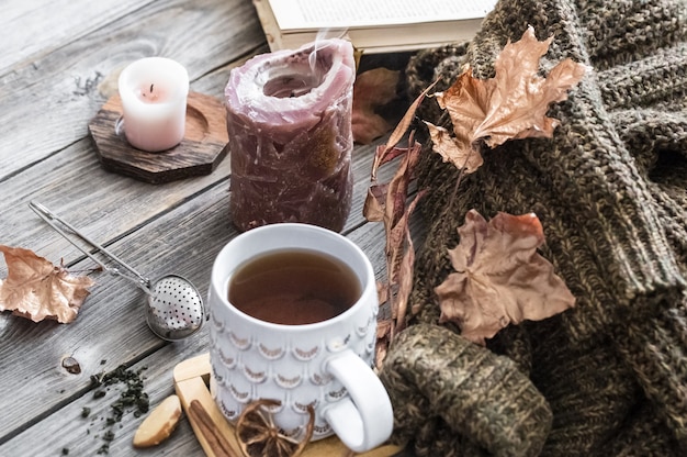 Cozy autumn morning breakfast in bed still life scene. Steaming cup of hot coffee, tea standing near window. Fall.