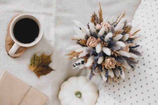 Cozy autumn still life with a cup dried leaves  and white pumpkin