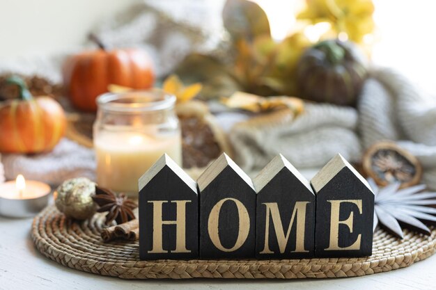 Photo cozy autumn still life with wooden word home on a blurred background