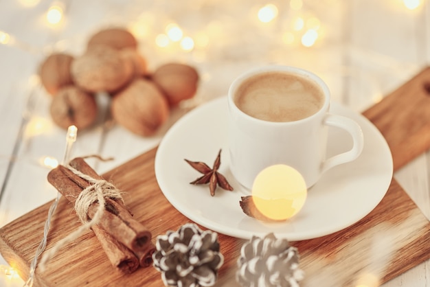 Cozy autumn or winter concept. Cup of coffee with garland lights and decoration/