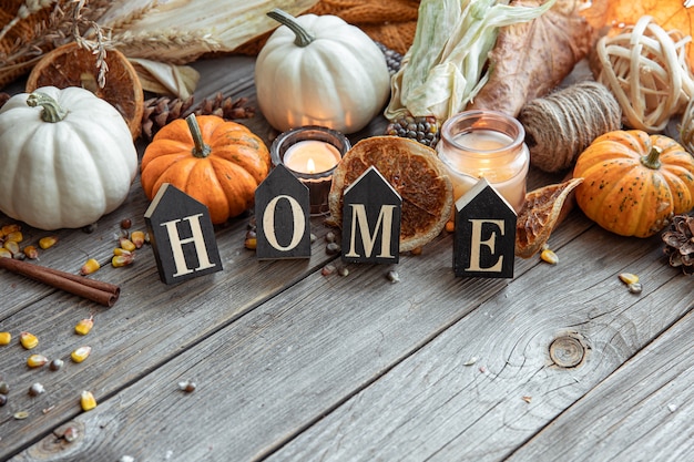 Cozy autumnal composition with decorative word home candles pumpkins and corn