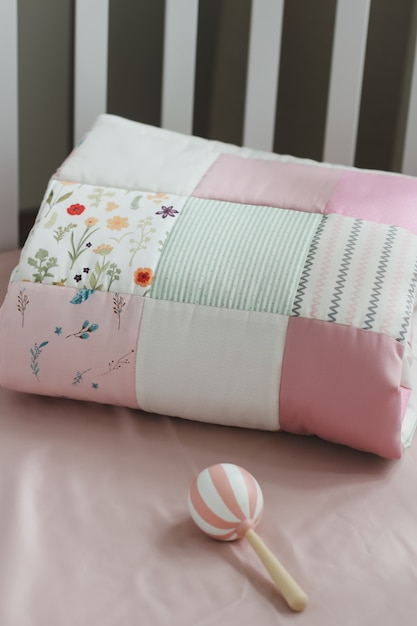 핑크 패치워크 담요가 있는 아늑한 아기 침대