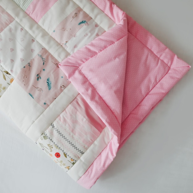 핑크 패치워크 담요가 있는 아늑한 아기 침대