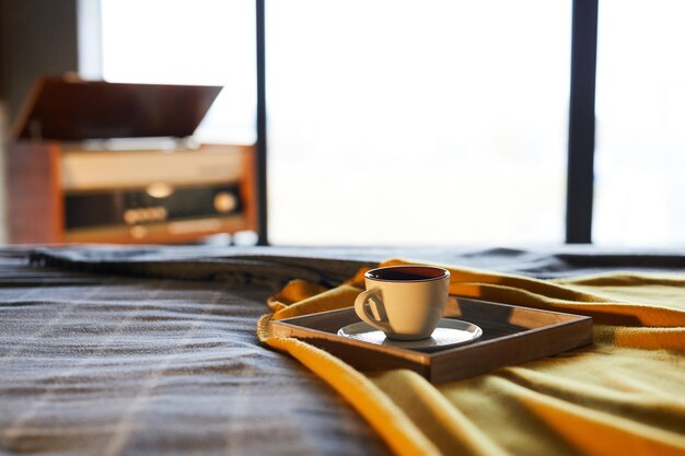 Cozy background of coffee cup on bed in bedroom against window copy space