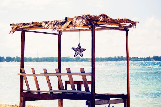 Cozy beach lounge cafe with wooden furniture, swing and umbrellas on Gili Air, Bali, Indonesia