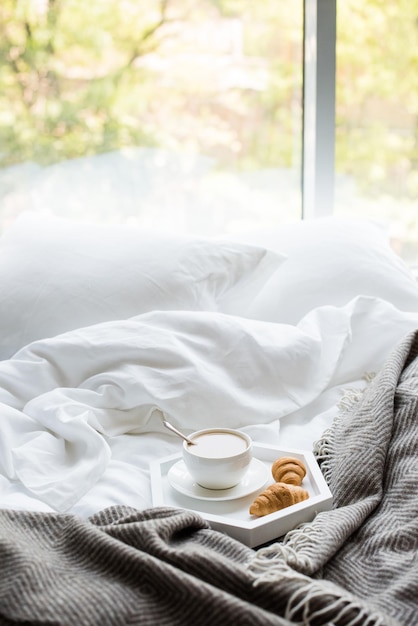 Cozy breakfast in bed cup of coffee and croissants