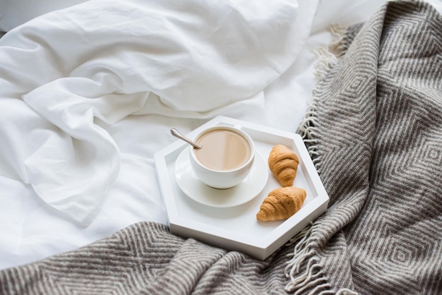 Cozy breakfast in bed cup of coffee and croissants