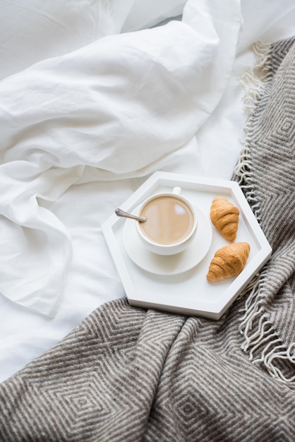 Cozy breakfast in bed cup of coffee and croissants