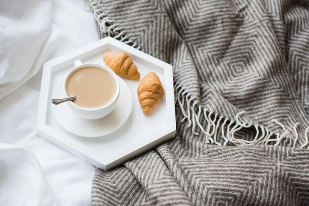 Cozy breakfast in bed cup of coffee and croissants