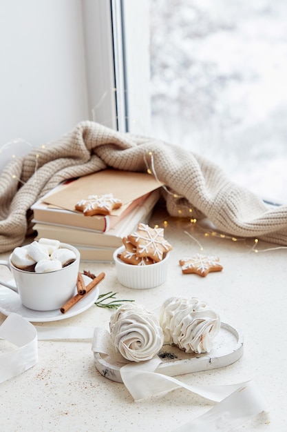 Foto accogliente sfondo estetico natalizio marshmallow bianchi cioccolata calda zenzero biscotti fatti in casa e libri a casa nella giornata nevosa fuori casa estetica