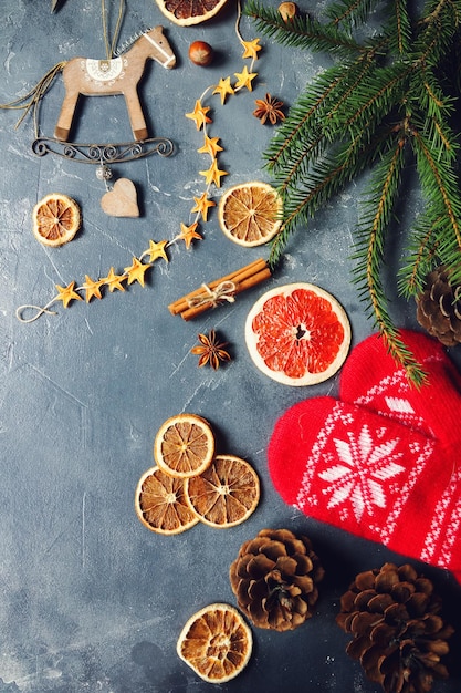 Cozy christmas background with dried oranges fir tree warm mittens cinnamon and cones Christmas decoration selective focus