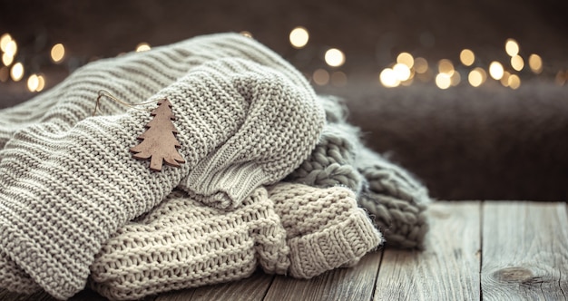 Cozy Christmas composition with a stack of knitted sweaters on a blurred background with bokeh.