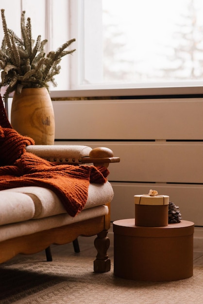 Photo cozy christmas decor in the living room fir branches in a vase near a sofa with a blanket and a window