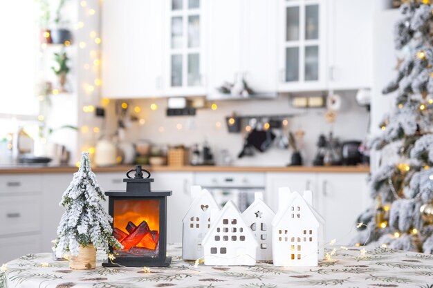 Уютный рождественский декор крошечный дом небольшого размера на столе праздничной белой современной кухни подарок
