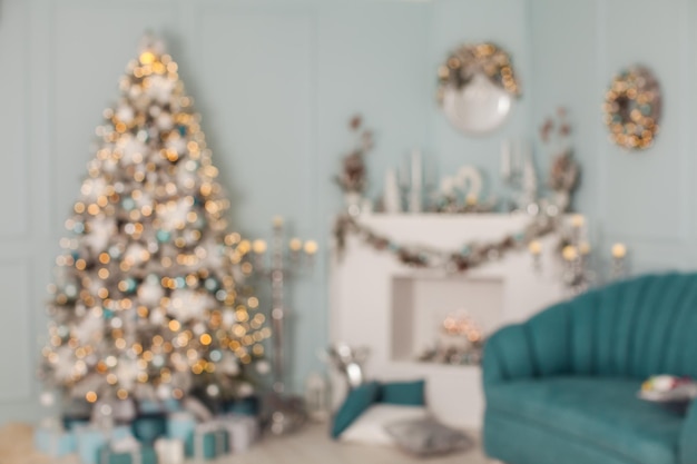 Уютный рождественский интерьер дома или студии, оформленный в сине-белых тонах с елкой и яркими огнями, синий диван размыт