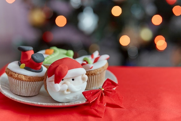 Cozy Christmas tea time Decorative festive cupcakes in front of the bokeh of Christmas tree Good holidays mood Selective focus