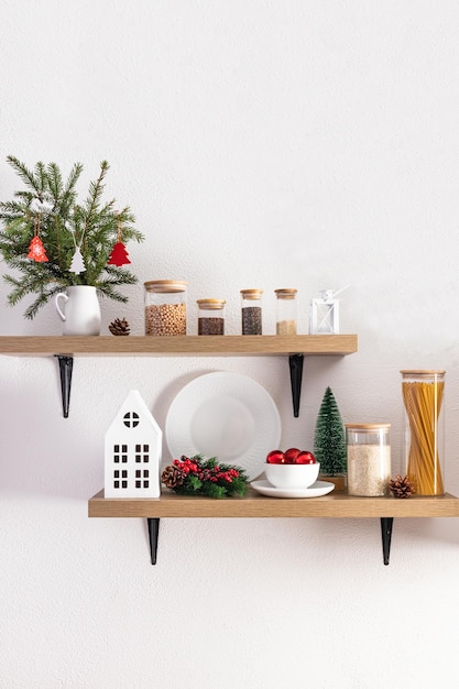 Cozy comfortable interior design of open kitchen shelves decorated for the New Year and Christmas foreground white textured wall