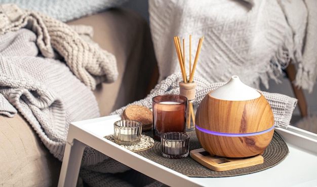 A cozy composition with an aroma diffuser and candles in a home interior