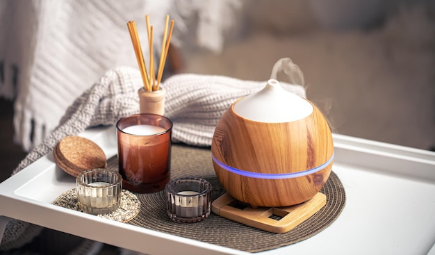 A cozy composition with an aroma diffuser and candles in a home interior