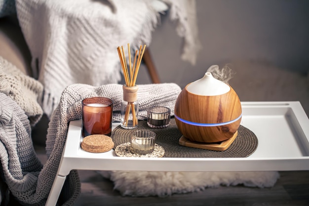 A cozy composition with an aroma diffuser and candles in a home interior