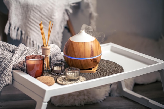 A cozy composition with an aroma diffuser and candles in a home interior