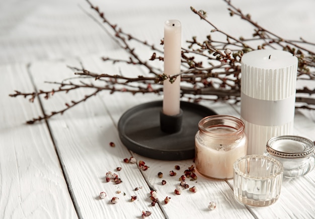 Cozy composition with decorative candles and young tree branches on a wooden surface in a rustic style.