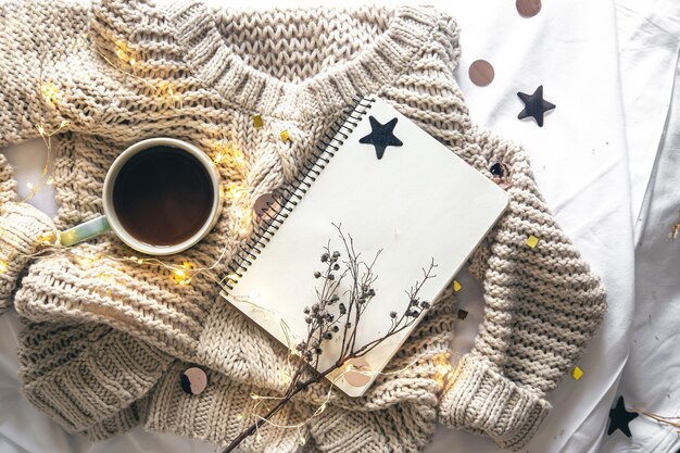 Photo cozy composition with a notebook a knitted element and a cup of coffee