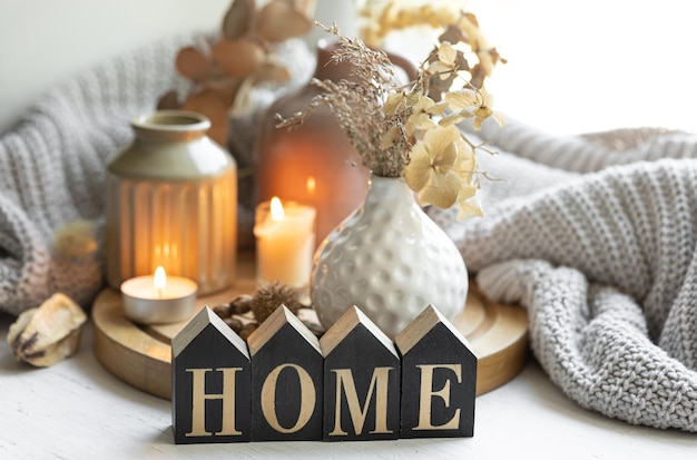 Photo a cozy composition with the wooden word home candles and a knitted element