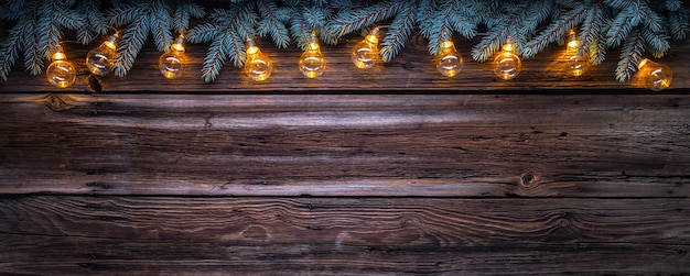 Cozy copy space background with spruce branches and christmas string lights on barn wood