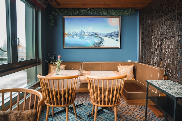 Уютная столовая с голубыми стенами, деревянной мебелью и горной пейзажной живописью в городской обстановке