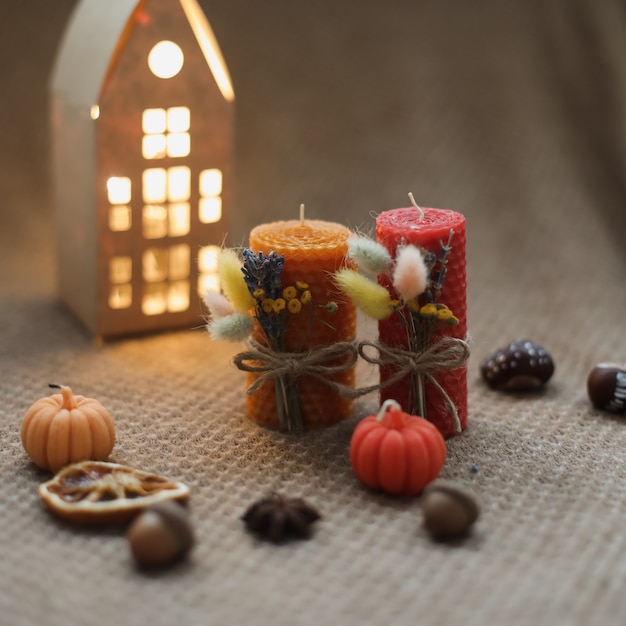 Cozy fall composition and autumn home decor with candles on warm background