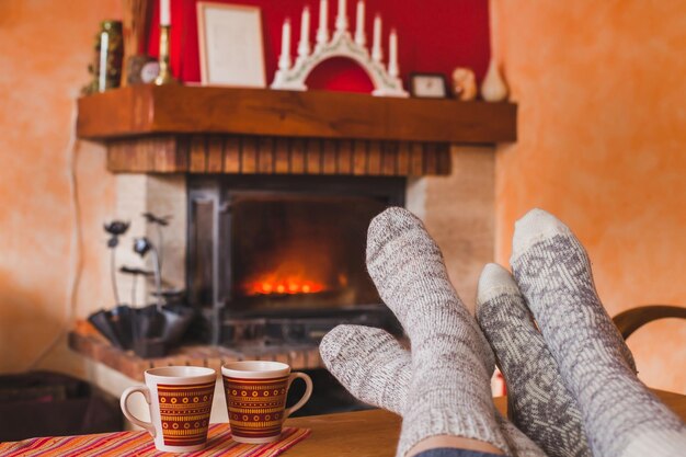 cozy family evening at home near fireplace in winter feet of couple in socks and two cups of tea weekend