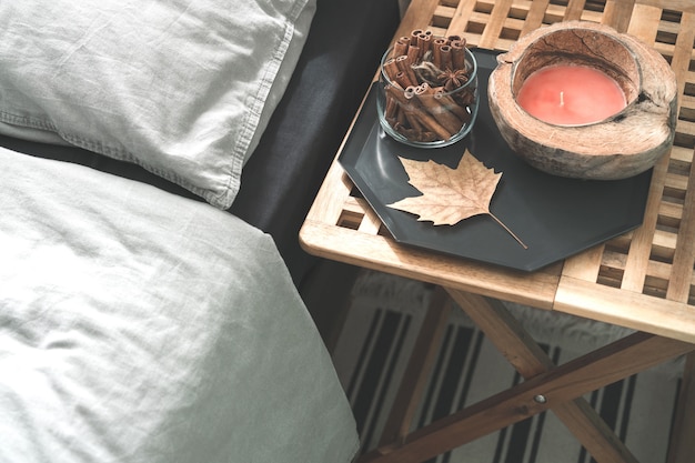 Cozy gray bedroom interior with comfortable bed near wooden night table with candle