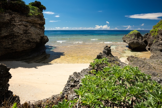 Cozy hidden beach with shallow sea, white sands, coastal rocks full of vegetation. Iriomote Island.