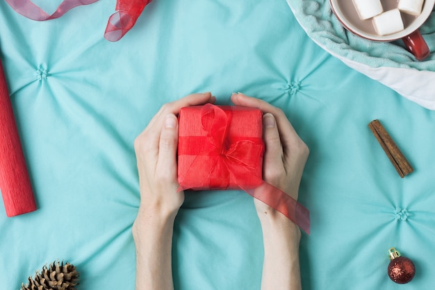 Cozy holiday layout with woman hands holding a gift