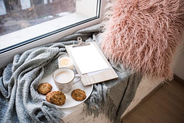 Cozy home arrangement with coffee cup and blank clipboard mockup