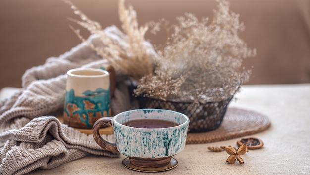 Уютная домашняя композиция с красивой керамической чашкой чая на столе. Декоративные элементы в интерьере.