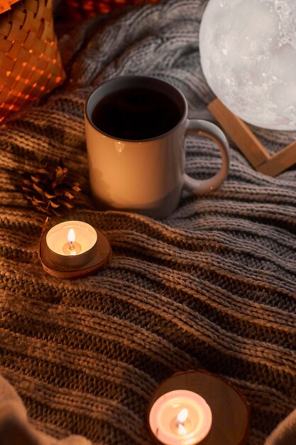 Cozy home decor with a warm atmosphere White mug with hot tea and knitted clothes