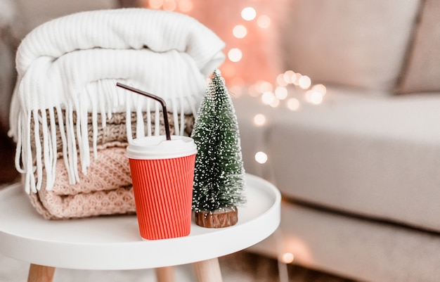 Cozy home decorations in the interior with knitting, christmas tree and cup of cocoa