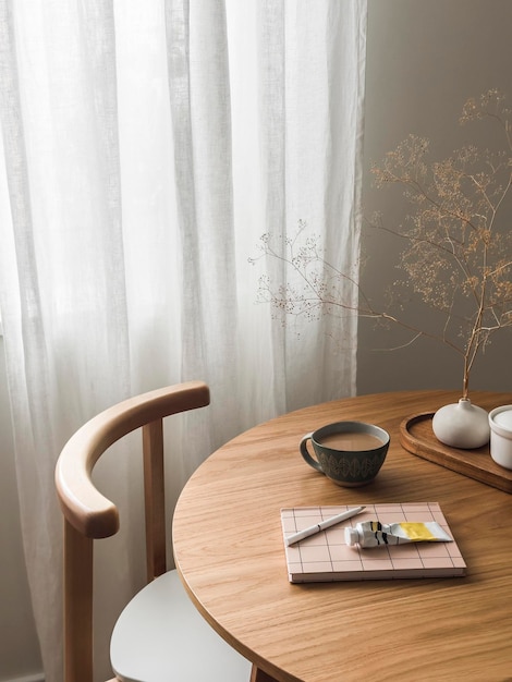 Cozy home interior a cup of tea with milk a notebook hand cream decor on a round wooden table in the living room