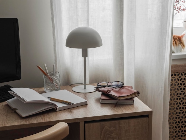 Cozy home office interior a desk with work educational supplies a red cat on the window Cozy house concept