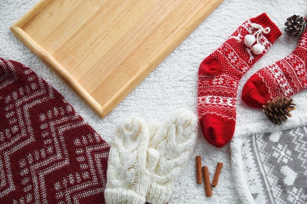 Cozy home still life: wool gloves, red wool socks, cones, candles with a warm woolen blanket and a sweater. Winter holidays